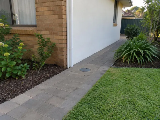 Capped access point in paved side path beside a brick and rendered house in Brookvale